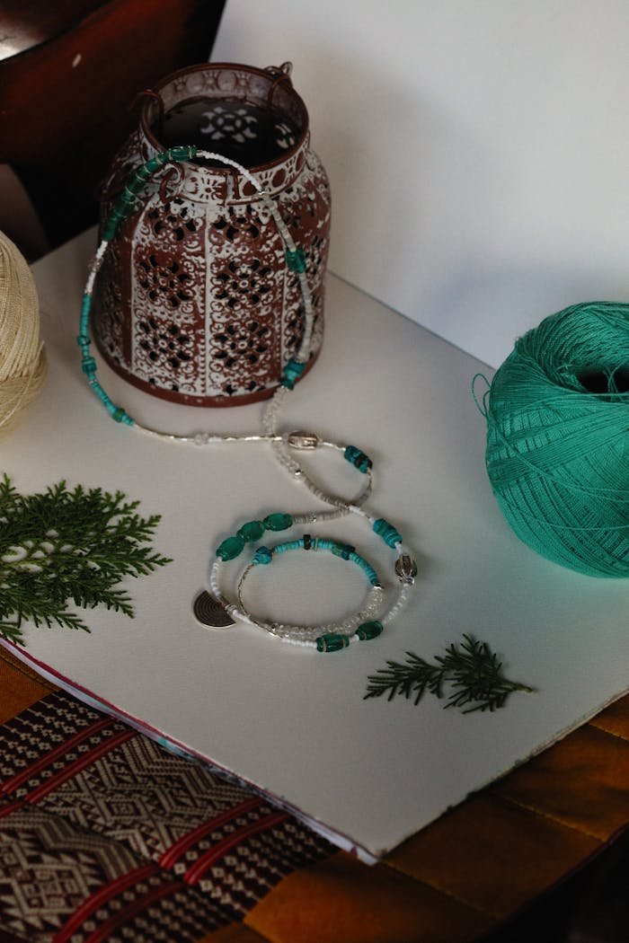 Close-up of handcrafted jewelry with beads and threads on a decorative surface showcasing artistic craftsmanship.