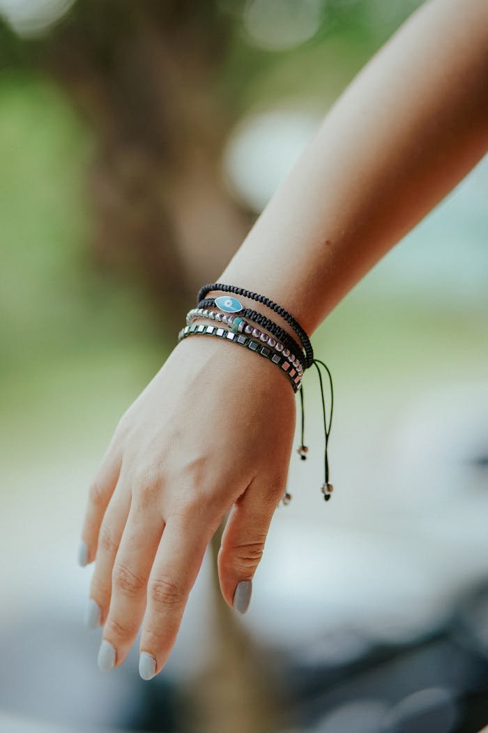 A woman's hand adorned with colorful bracelets, elegantly displayed outdoors.